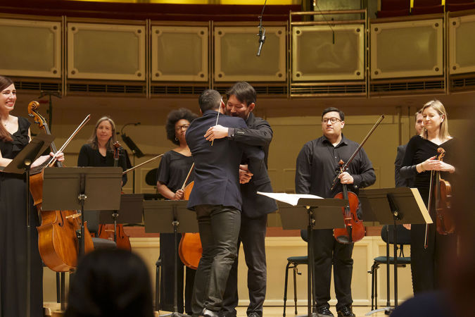 Composer-Curator Jimmy López hugs his collaborator and friend, conductor Nicholas Koo