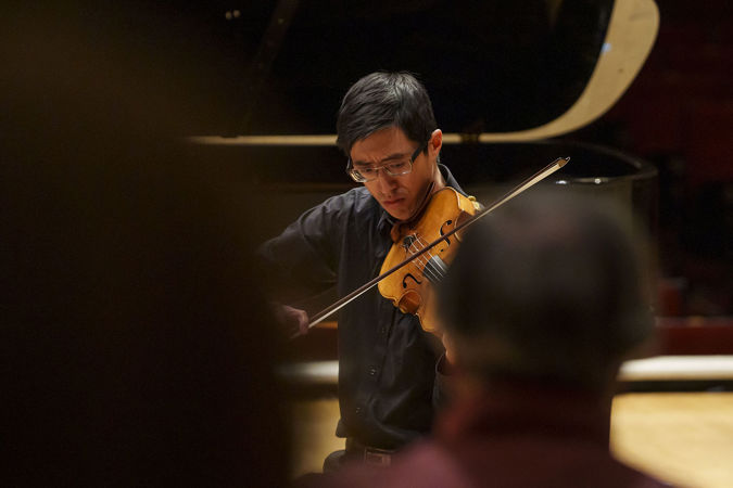 Closeup of CSO viola Danny Lai performing on stage