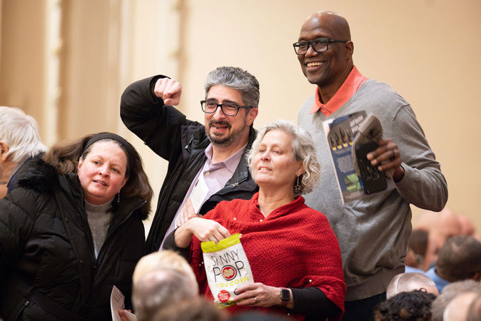 Four audience members smiling while looking for their seats