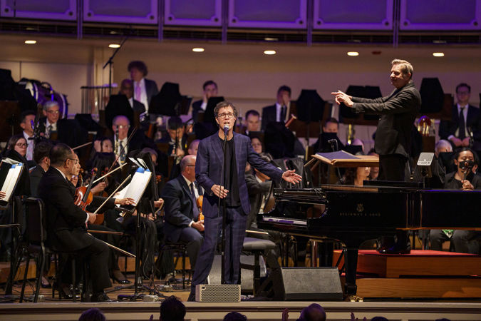 Wide shot of singer-songwriter Ben Folds singing on stage with the CSO and conductor Steven Reineke