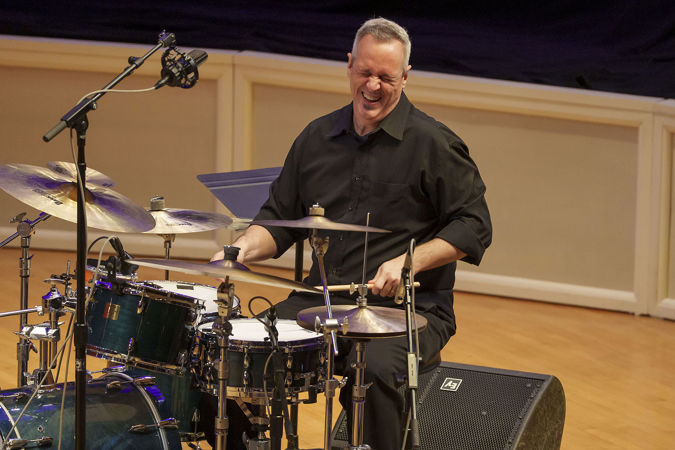 drummer Mauricio Zottarelli closes his eyes and laughs in the middle of performing a joyful piece