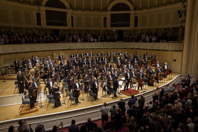 the full Orchestra takes a bow as audience members rise to their feet