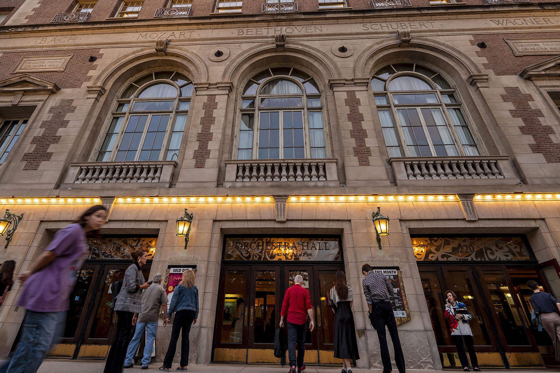 people gather on the sidewalk outside Orchestra Hall