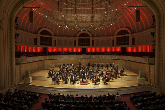 Wide shot of members on the CSO and conductor Daniel Bartholomew-Poyser performing on stage