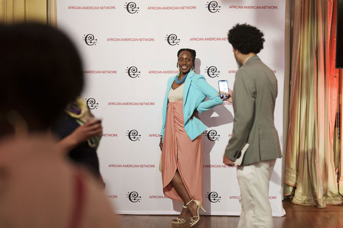 A CSO African American Network member takes a photo behind a CSO backdrop in Grainger Ballroom