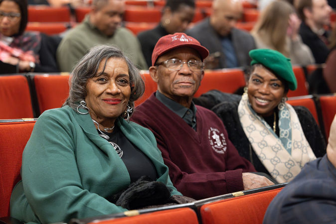 Three audience members smiling in their seats before the concert