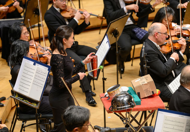 Cynthia Yeh strikes peculiar percussion instruments, including an upside down metal water bottle, during the Lost Coast concerto