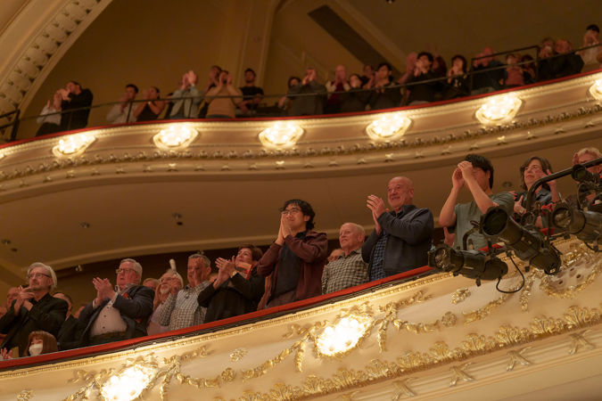 Audience members in balcony clapping