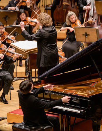 A closeup of Santtu-Matias Rouvali conducting the CSO and Seong-Jin Cho playing the piano