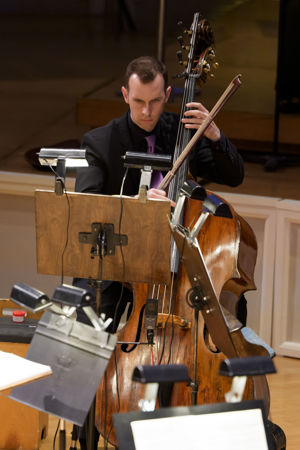 Closeup action shot of CSO principal bass Alexander Hanna performing on stage