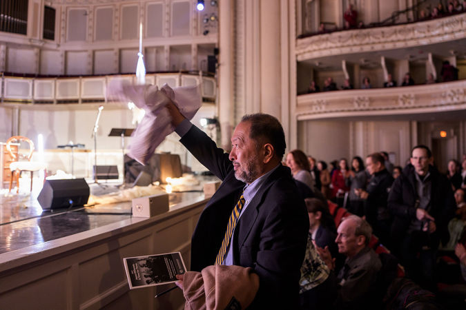 a man in the front row waves enthusiastically as the performers take a bow