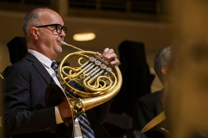 Close up action shot of CSO horn David Griffin warming up before the concert on stage