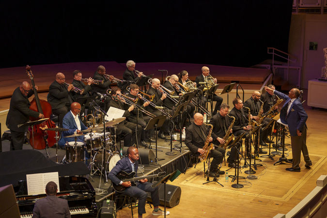 John Clayton extends an arm towards the trombone section while directing the Chicago Jazz Orchestra in Oscar Peterson's Africa Suite