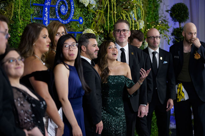 Group shot of CSO Overture Council members smiling behind the step-and-repeat plant and butterfly backdrop