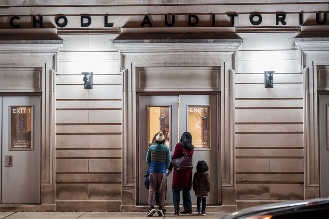 a family peers into the exterior doors of Chodl Auditorium