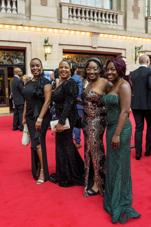 A group shot of Symphony Ball attendees dressed up in gowns on the red carpet
