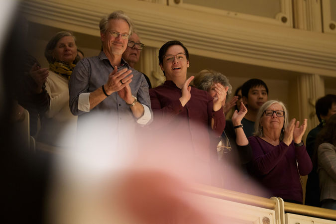 audience members overlooking the stage from the terrace smile and give a standing ovation