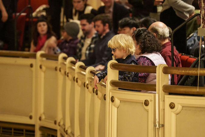 a young audience member looks down in awe from the balcony